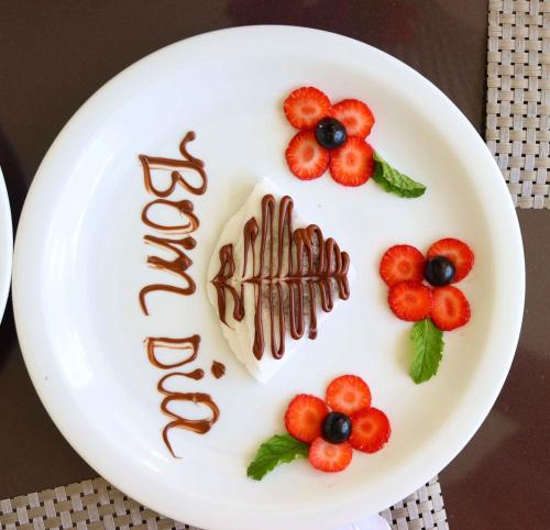 a white plate with chocolate and berries on it at Star Palace Hotel Jeri in Jericoacoara