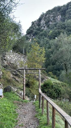 a wooden fence next to a path with a mountain at Iconic Italian Townhouse w Rooftop Terrace & Mountain View, Pigna in Pigna