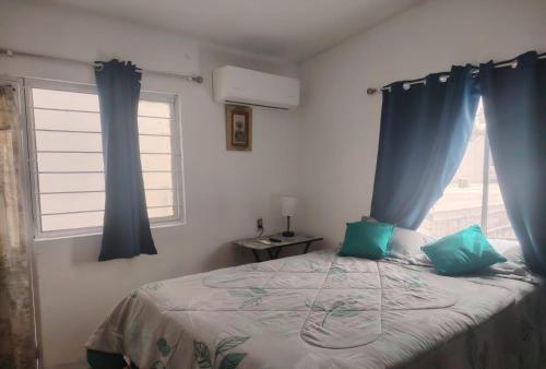 a bedroom with a bed with blue curtains and a window at Departamento 2 a 200 mts de Imss 25 in Monterrey