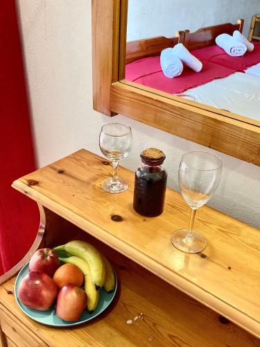 a plate of fruit on a wooden shelf with two glasses at Eleana Apartments in Hersonissos