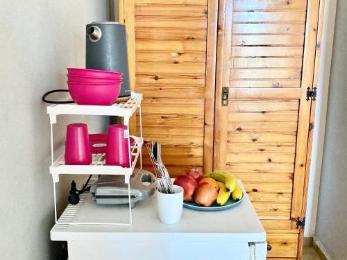 a bowl of fruit on a counter with pink bowls at Eleana Apartments in Hersonissos