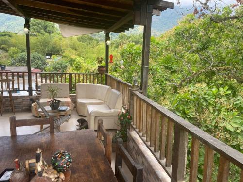 a porch with a couch and a chair on a deck at Hostal Los Wichos in Minca
