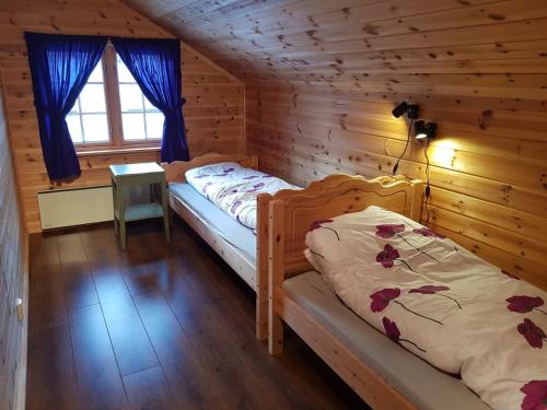 a bedroom with two beds in a log cabin at Leiligheten in Fyresdal