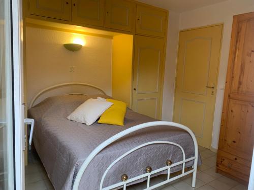 - une chambre avec un lit et un oreiller jaune dans l'établissement Au bord de la mer, à Saint-Aygulf