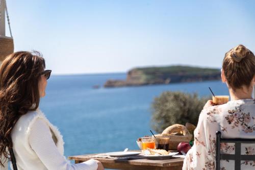 two people sitting at a table looking out at the water at Poseidon Apartments and Villas by the Sea in Sounio