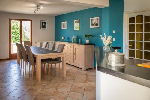 d'une cuisine avec une table et des chaises et des murs bleus. dans l'établissement Gîte de Caillou, à Berbiguières