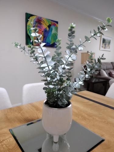 a white vase with a plant on a table at The Modern Recharging Station in Marietta