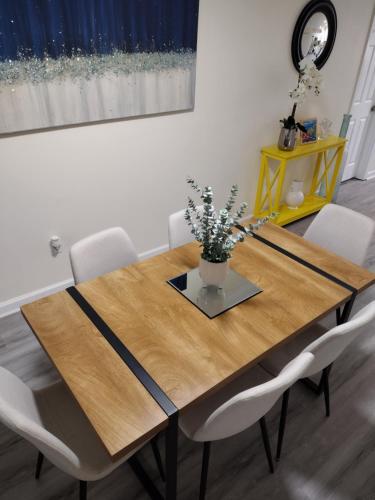 a wooden table with white chairs and a vase with flowers on it at The Modern Recharging Station in Marietta