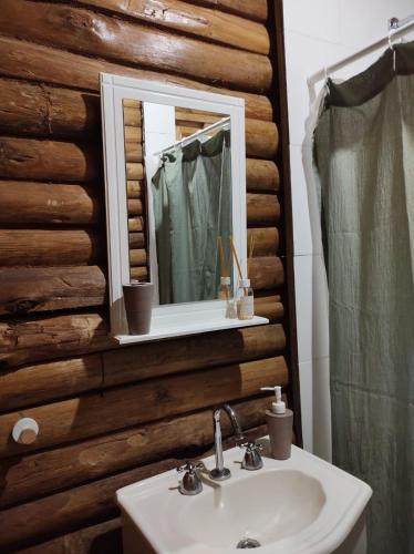 a bathroom with a sink and a mirror on a wooden wall at Cabaña La Obsidiana in San Miguel del Monte