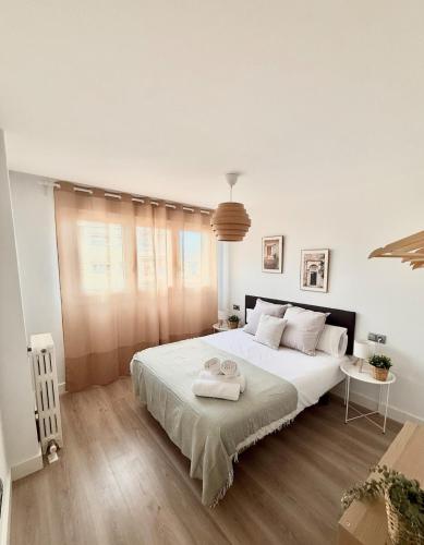 ein weißes Schlafzimmer mit einem großen Bett mit zwei Handtüchern darauf in der Unterkunft Vive Zaragoza XII in Saragossa