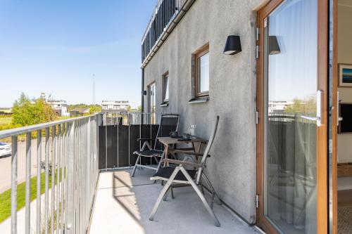 a balcony with a desk and chairs on a building at Cozy, designed, Beach House apartment in Beddinge Strand