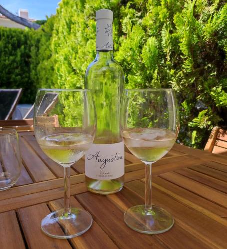 - une bouteille de vin et 2 verres à vin sur une table en bois dans l'établissement Studio 24m2 - parking - clim - piscine - plage 50m, à Roquebrune-sur Argens
