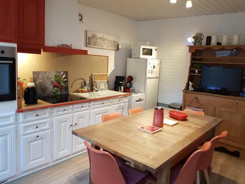 Il dispose d'une cuisine avec une table en bois et des chaises. dans l'établissement L'Estivale maison cosy avec véranda et climatisation, à Étretat