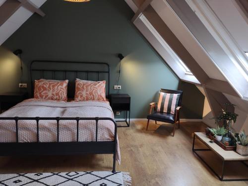 a bedroom with a bed and a chair in a attic at 't KISTJE Bed by the Sea in Koudekerke