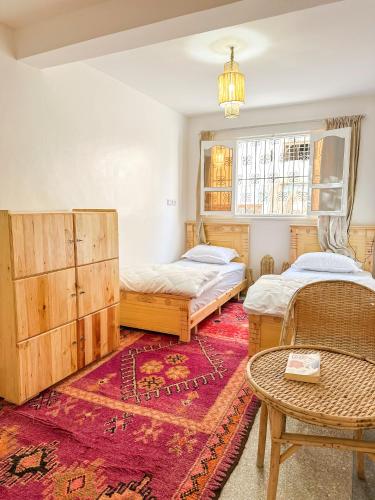 a bedroom with two beds and a table and a rug at Surf and Stay Anza - Surf Territory in Agadir