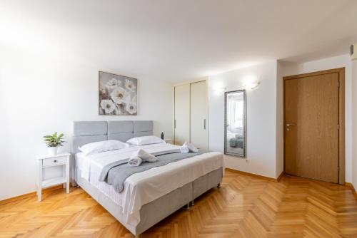 a white bedroom with a large bed and a wooden floor at Villa Valamare in Podstrana