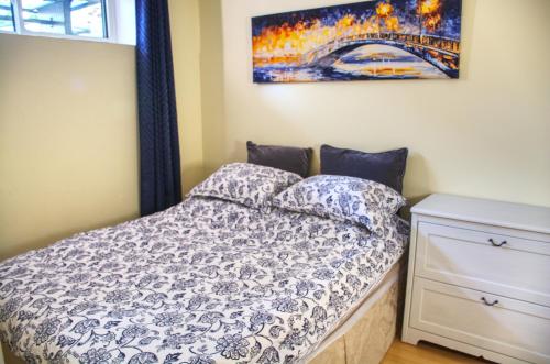 a bedroom with a bed and a painting on the wall at Calm, cozy, urban, family-friendly stay in Vancouver