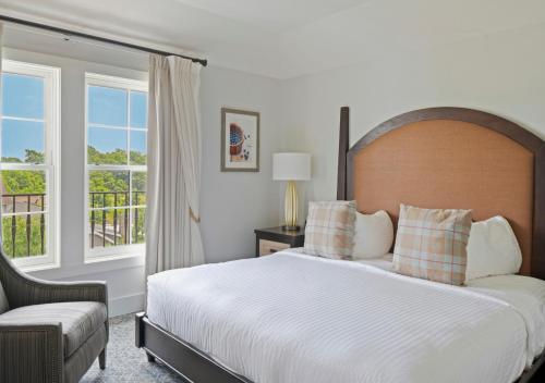 a bedroom with a bed and a chair and a window at The Inn at Chesapeake Bay Beach Club in Stevensville