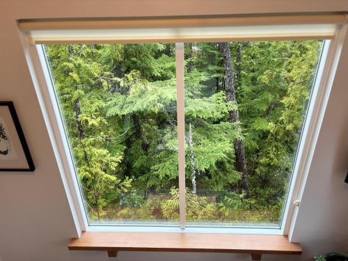 a window with a view of a forest at Brown's Beach Guest Suite in Ucluelet