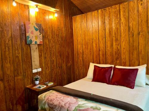 a bedroom with wooden walls and a bed with red pillows at Cabañas La Montaña in Monteverde Costa Rica