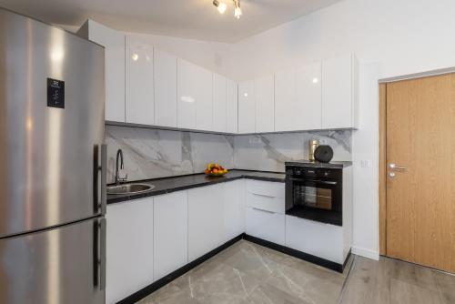 a kitchen with white cabinets and a stainless steel refrigerator at Villa Valamare in Podstrana