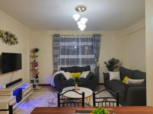 a living room with a couch and a table at Sunbird Serenity Stays in Nairobi