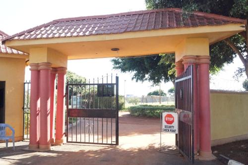 a gate with red columns in front of a building at Peniel Beach Hotel in Entebbe