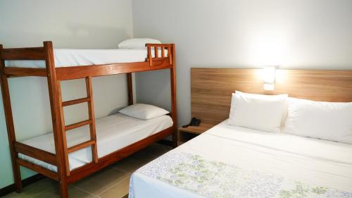 two bunk beds in a small room with a bed at Hotel Costa Norte Massaguaçu in Caraguatatuba
