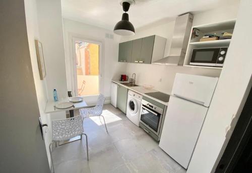 Il comprend une cuisine équipée d'un réfrigérateur blanc, d'une table et de chaises. dans l'établissement Appartement prince de galles, à Vichy