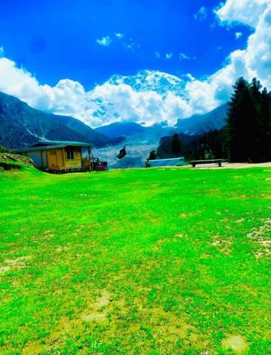 a field of green grass with mountains in the background at Fairy meadows BroadView Hotel in Tato