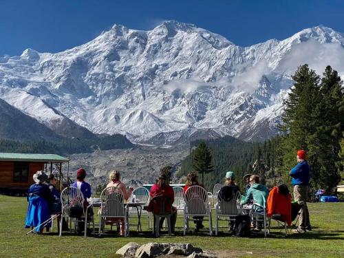 a group of people sitting at a table in front of a mountain at Fairy meadows BroadView Hotel in Tato