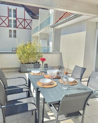 une table et des chaises bleues sur une terrasse dans l'établissement L'estuaire ensoleillé, à Le Touquet-Paris-Plage