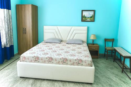 a bedroom with a white bed and a blue wall at Aaranya Retreat by Agrawal s in Haridwār