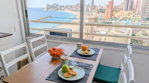 a table with two plates of fruit and a view of the ocean at PINTOR SOROLLA sea front apartment in Benidorm