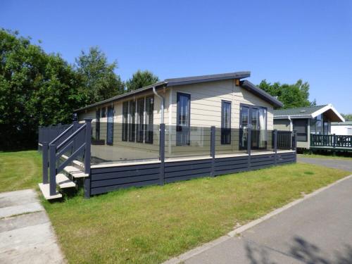 a house with a fence in front of it at Gee Luxury Lodge Southview Skegness in Winthorpe