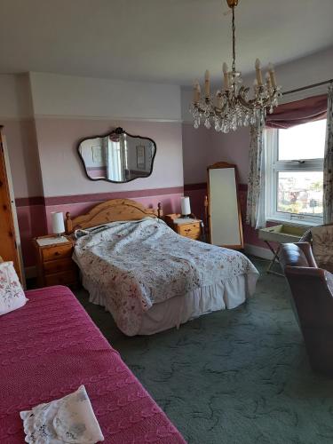 a bedroom with a bed and a mirror and a chandelier at Sea view flat at Claverton House in Ryde