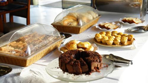 a table topped with a chocolate cake and other pastries at Hotel Costa Norte Massaguaçu in Caraguatatuba