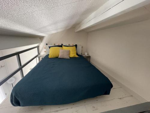une chambre avec un grand lit avec des oreillers jaunes dans l'établissement Studio 24m2 - parking - clim - piscine - mer à 100m, à Roquebrune-sur Argens