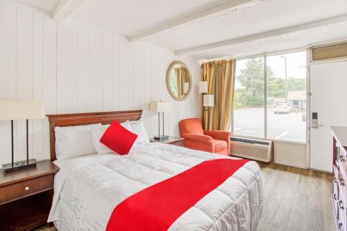 a hotel room with a red and white bed and a window at OYO Inn Kernersville in Kernersville