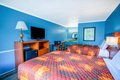 a hotel room with two beds and a flat screen tv at OYO Inn Kernersville in Kernersville
