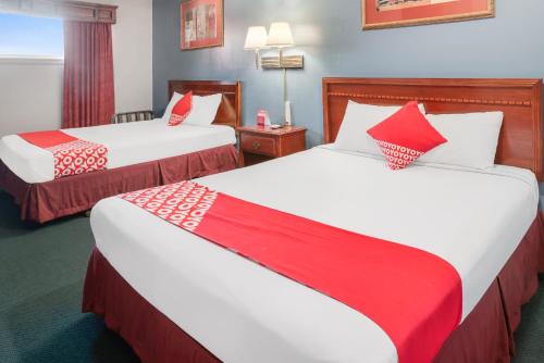 two beds in a hotel room with red and white pillows at OYO Hotel Liberal, Kansas in Liberal