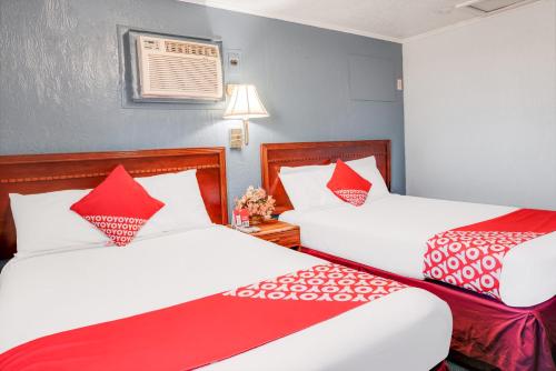 two beds in a room with red and white pillows at OYO Hotel Liberal, Kansas in Liberal