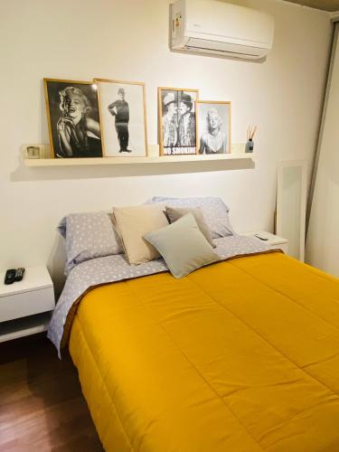 a bedroom with a yellow bed with pictures on the wall at Depto Genova, Zona Norte, cochera con Reserva previa in Rosario