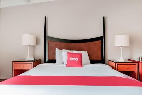 a red pillow sitting on a bed with two lamps at OYO Hotel Alice TX Hwy 281 West in Alice