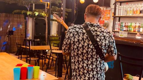 um homem parado em frente a um bar com um violão em Good Vibes em Siem Reap