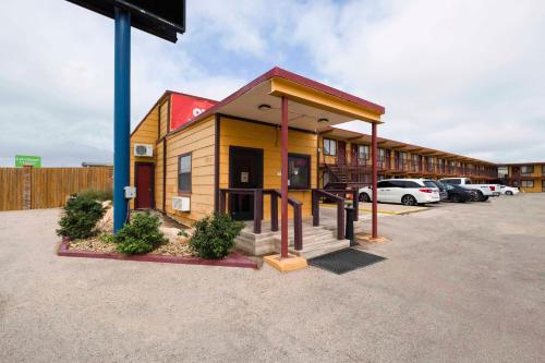 un pequeño edificio en un estacionamiento con coches aparcados en Oyo Hotel Odessa TX, East Business 20, en Odessa