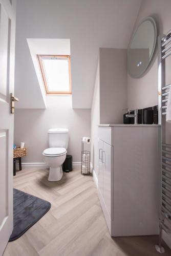 a white bathroom with a toilet and a sink at Serenity House, Whitehall Ballycastle in Ballycastle