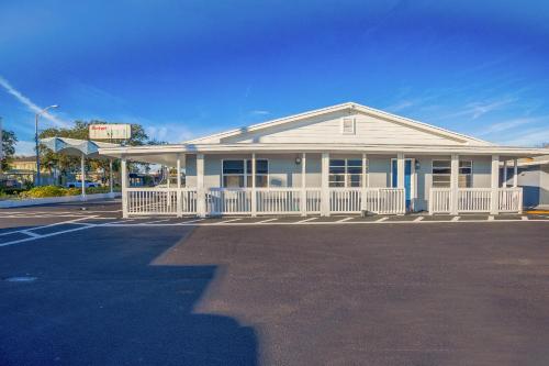 a white house with a white fence in a parking lot at Sunrise Inn by OYO Titusville FL in Titusville