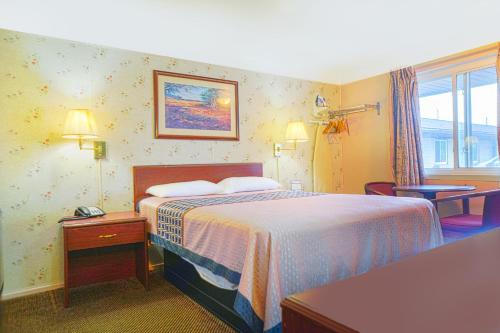 a hotel room with a bed and a window at Bay Motel By OYO Bay City in Bay City