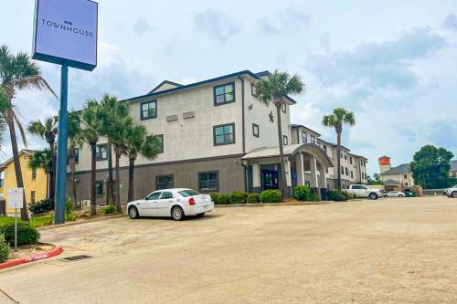 a white car parked in a parking lot in front of a building at OYO Townhouse Beaumont Medical Center Area in Beaumont